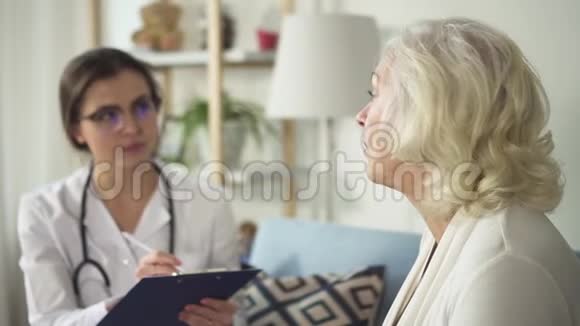 年轻医生在她明亮的家拜访退休妇女视频的预览图