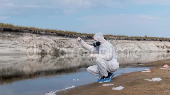 戴防护服装和防毒面具的人在试管中检查水样视频的预览图