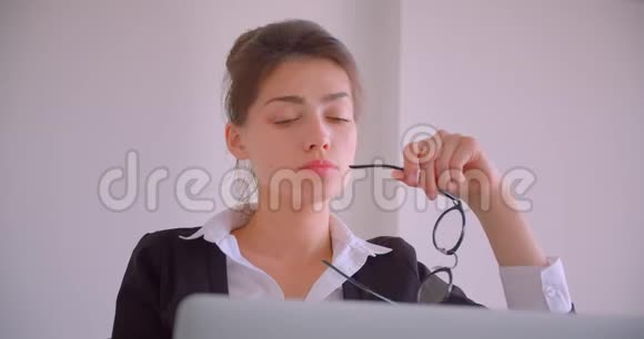 一位年轻忙碌的高加索女商人用笔记本电脑拍摄的特写镜头她在办公室里穿着白色的衣服体贴入微视频的预览图