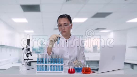 女性微生物学家分析试管中的液体一位女性科学家进行医学研究并撰写视频的预览图