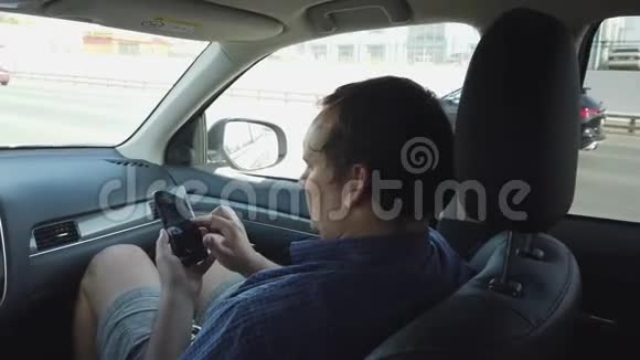 英俊的年轻人在汽车的驾驶座上使用手机视频的预览图