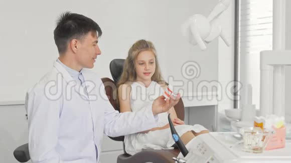 开朗的男牙科医生教小女孩如何刷牙视频的预览图