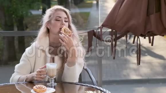 优雅的女人在街头咖啡馆吃甜糕点蛋糕视频的预览图