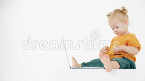 有趣的女婴坐在笔记本电脑前看着她空空如也的口袋视频的预览图
