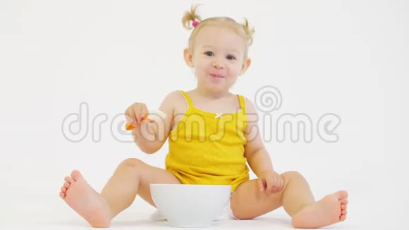 快乐的金发女婴在白色背景下吃麦片视频的预览图