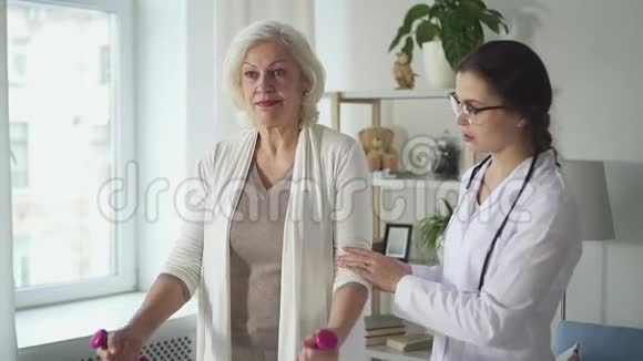 年轻医生正在向女性老年患者展示保健锻炼视频的预览图