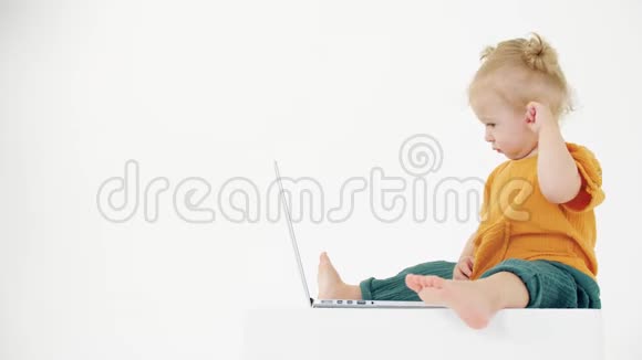 困惑的女婴看着白色背景上的笔记本电脑屏幕用户问题相关剪辑视频的预览图