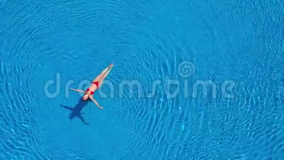 从顶部看一个穿着红色泳衣的女人游泳躺在游泳池里放松概念视频的预览图