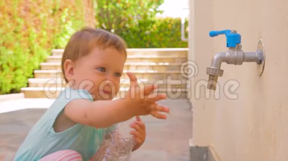 小女孩在玩水幼儿玩水从水龙头流出小孩拿着空的塑料瓶视频的预览图