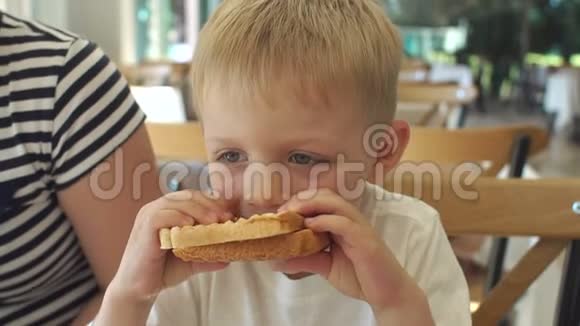 一个金发小男孩在餐馆吃烤三明治的特写镜头视频的预览图