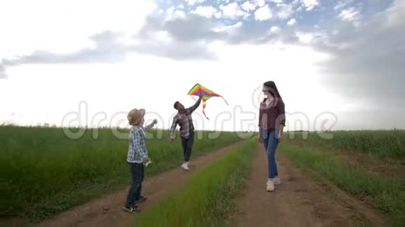 家庭周末年轻的母亲和父亲和儿子都喜欢周末在农村放风筝散步视频的预览图