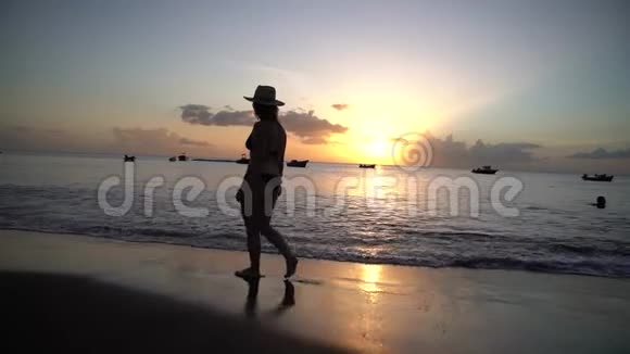 女子在沙滩日落漫步慢动作视频4K视频的预览图