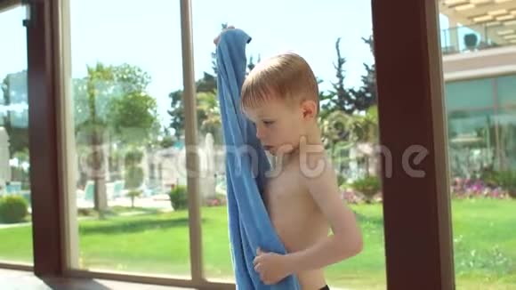 一个金发小男孩在游泳池游泳后用毛巾包着自己视频的预览图