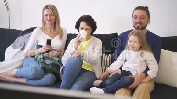 在电视上看喜剧电影的家人之间节日快乐视频的预览图
