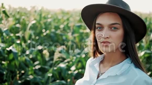 特写照片戴着帽子的漂亮女孩站在玉米地边微笑着看着镜头现代农业视频的预览图