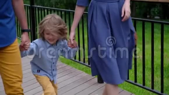 快乐的小男孩在户外散步牵着父母的手视频的预览图