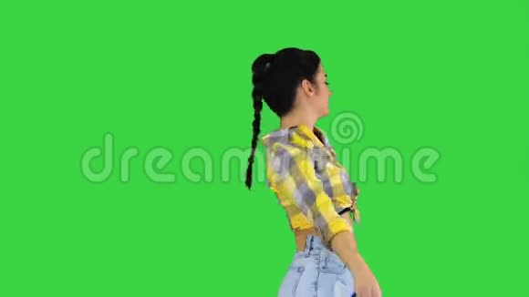 漂亮可爱的女孩穿着牛仔裤短裤运动鞋在绿色屏幕上跳舞Chroma键视频的预览图