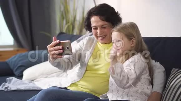 退休妇女和小孙女正在通过网上会议与人们交谈视频的预览图
