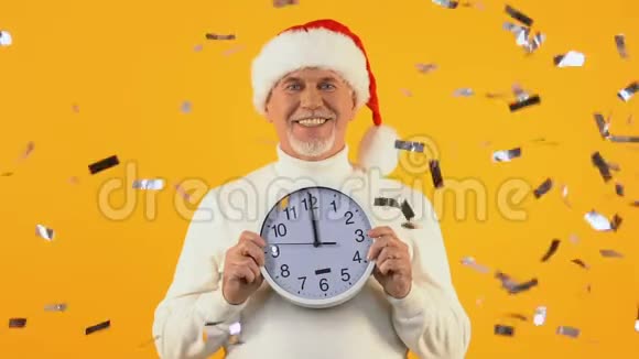 圣诞老人戴着圣诞帽举着午夜的钟新年晚会快乐视频的预览图