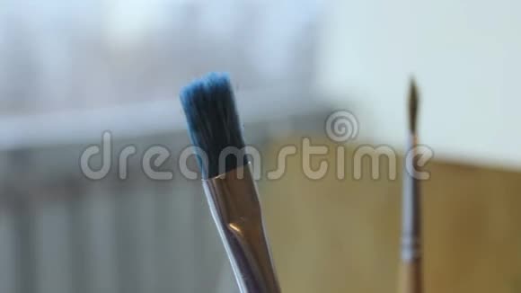 艺术画笔在黑色罐子里画画在温暖的背景上用手柄视频的预览图