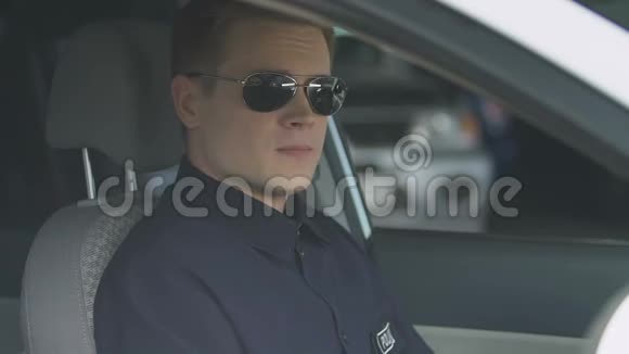 戴墨镜的负责任警察坐在巡逻车上微笑着对着镜头视频的预览图