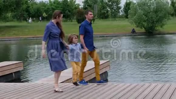 幸福家庭概念母亲父亲和小男孩在河边散步玩得开心视频的预览图