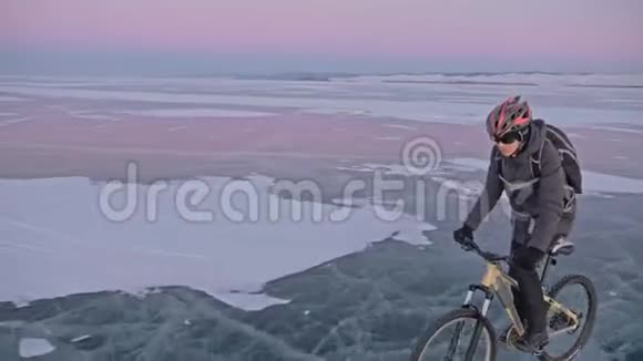 人在冰上骑自行车骑自行车的人穿着灰色羽绒服背包和头盔冰冻的冰视频的预览图