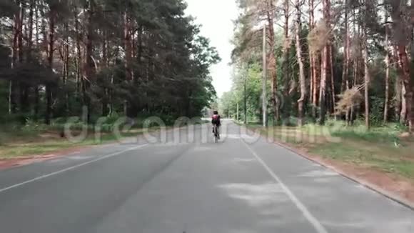 年轻迷人的三项运动员正在森林里骑自行车训练后面跟着射击无人机视图视频的预览图