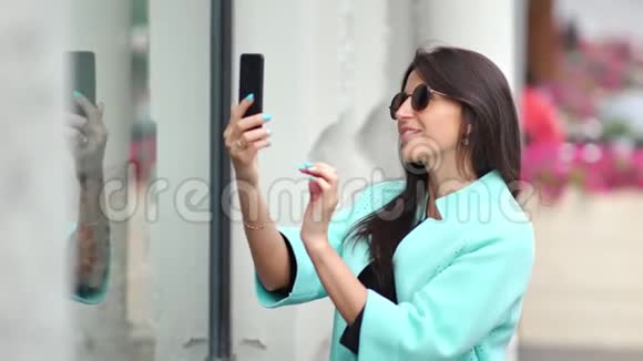 微笑购物者女性使用智能手机媒体特写拍照玻璃橱窗时装店视频的预览图