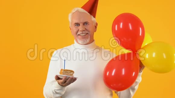 微笑的退休老人吹着蛋糕蜡烛落下纸屑庆祝生日视频的预览图