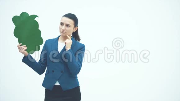 一位漂亮的年轻老师手里拿着一个绿色的弹出指着它微笑着老师站在白色的背景上视频的预览图