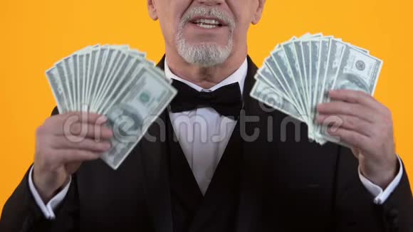 富有的老年绅士穿着西装展示美元彩票中奖者营业收入视频的预览图