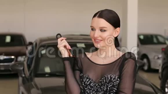 一个漂亮女孩的肖像陈列室里有一辆新车的钥匙视频的预览图
