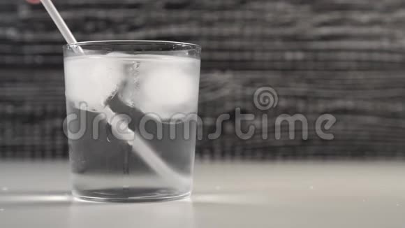 酒保手在杯子里搅动装有冰块的饮料管慢动作黑白的视频的预览图