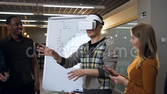 年轻的白种人戴着虚拟现实眼镜玩游戏而他的吸烟者看着他视频的预览图