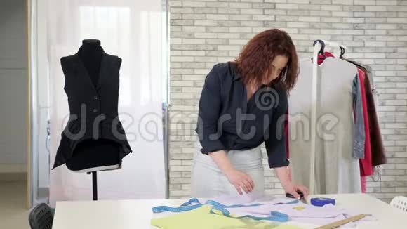 裁缝女士测量布用胶带在桌子上为未来的衣服做图案视频的预览图