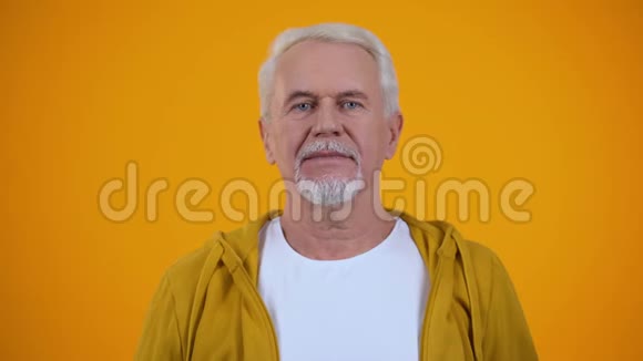 乐观的老人在橘色的背景下真诚地笑幸福视频的预览图