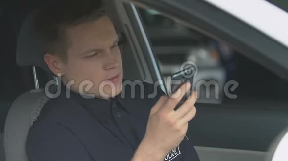坐在警车上的年轻警察在智能手机上的社交网络上聊天视频的预览图