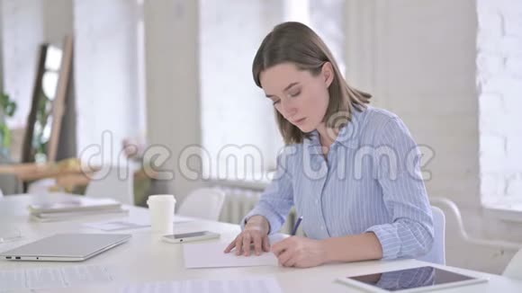 青年妇女在办公室写论文视频的预览图
