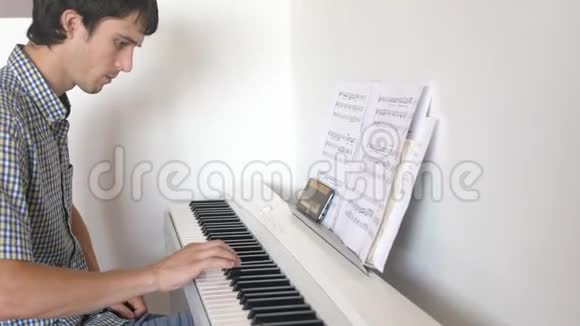 英俊的人试着弹钢琴年轻人用手机学弹钢琴视频的预览图