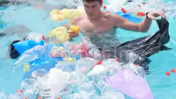 地球污染的概念年轻人在垃圾中游泳视频的预览图