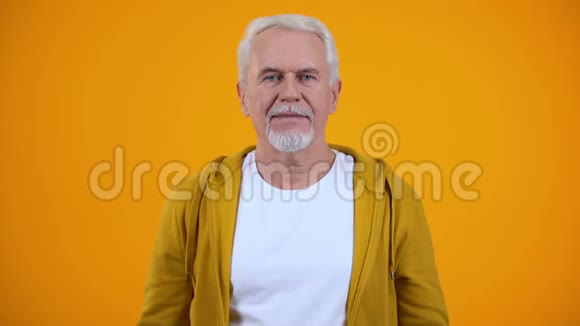 欢乐的老人欣赏的人在橙色的背景上显示空气亲吻标志视频的预览图
