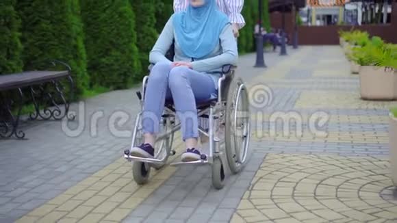 年轻的穆斯林残疾人戴着传统的轮椅围巾与街上的穆斯林朋友交流视频的预览图