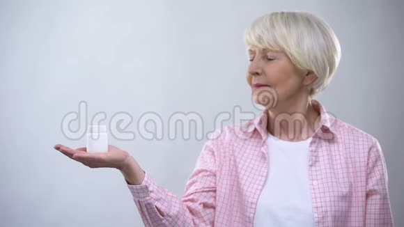 老年妇女拿着药丸思考副作用治疗影响视频的预览图