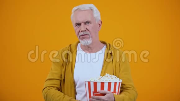 50多岁的男人对乏味的电影很不满意对着镜头扔爆米花视频的预览图