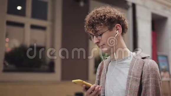 一个戴着眼镜头戴耳机穿着格子夹克的年轻时尚红发男人的特写镜头与朋友聊天视频的预览图