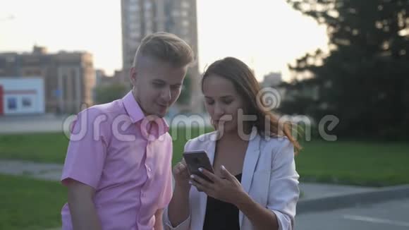 快乐的年轻夫妇在户外用智能手机聊天慢动作视频的预览图