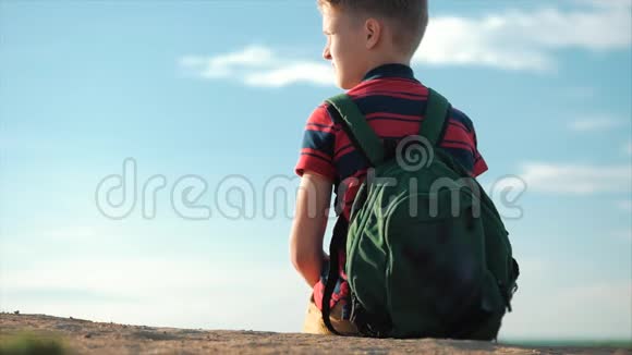 在日落时分穿着一件背着背包的红色t恤坐在高高的山上享受着自然和自由视频的预览图