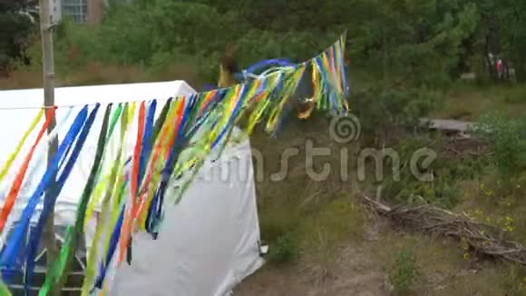 五颜六色的丝带挂在派对帐篷附近人们在大自然中散步视频的预览图