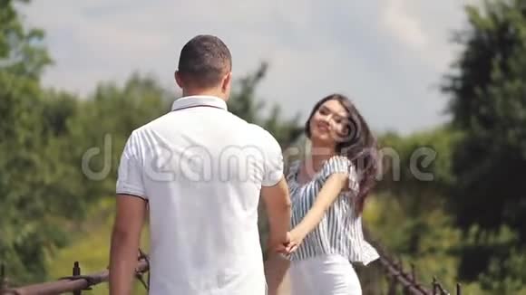 恋爱中的情侣在公园里玩微笑的女人带领男人在夏天在公园牵手视频的预览图